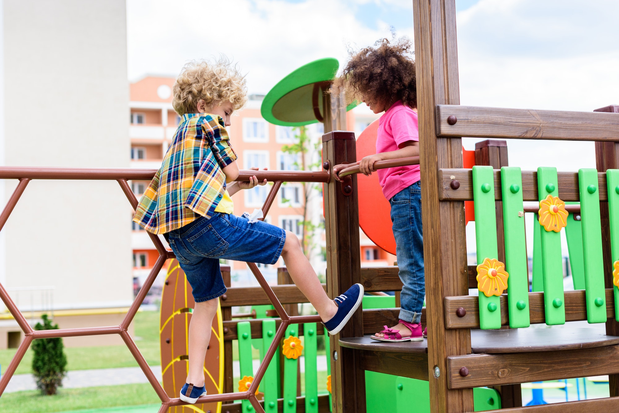 curly-multiethnic-little-children-climbing-and-having-fun-at-playground