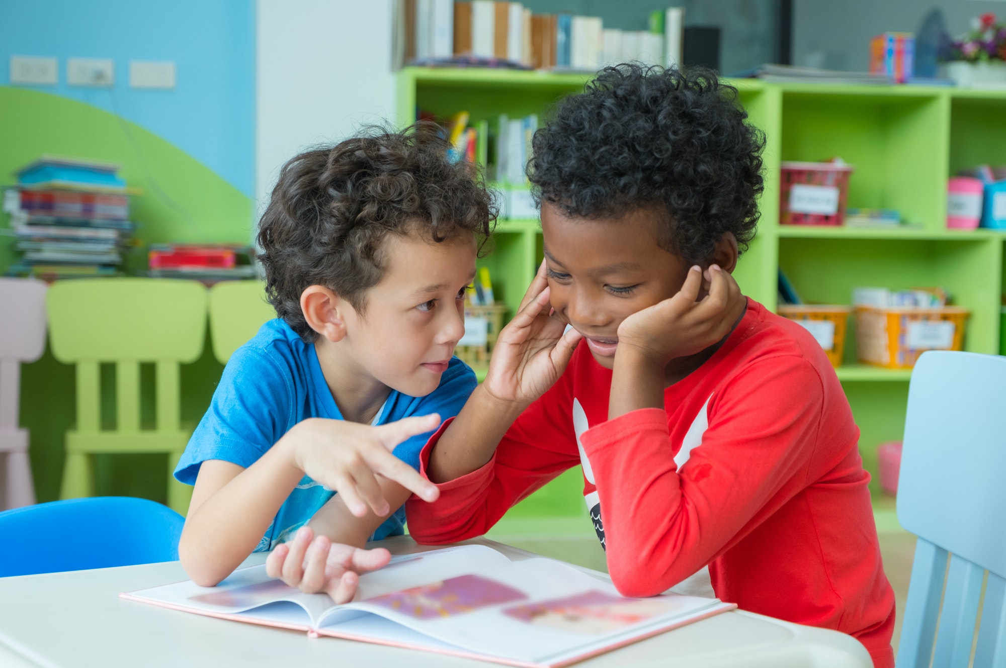 two-boy-kid-sit-on-table-and-coloring-in-book-in-preschool